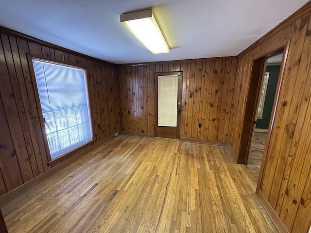 spare room with light wood-style flooring, wooden walls, and baseboards