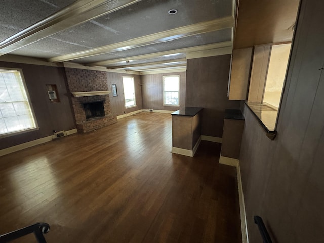 unfurnished living room with a brick fireplace, baseboards, and dark wood-style flooring