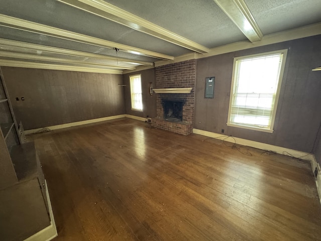 unfurnished living room featuring a brick fireplace, electric panel, beamed ceiling, and wood finished floors