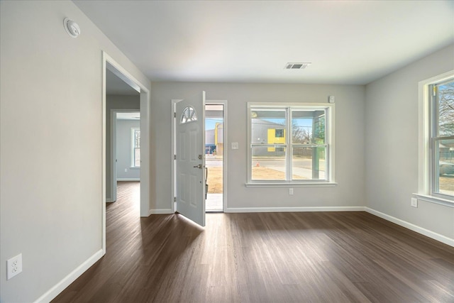 spare room featuring dark wood-style floors, visible vents, and baseboards