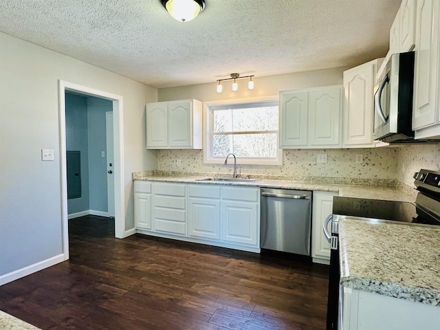 kitchen featuring decorative backsplash, white cabinets, dark wood-style floors, appliances with stainless steel finishes, and a sink