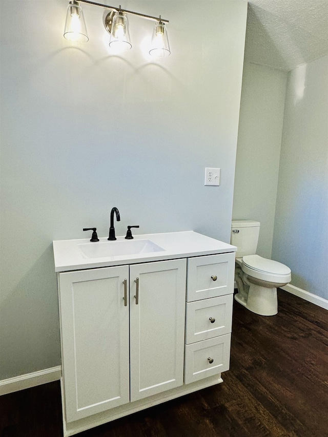 bathroom with toilet, baseboards, wood finished floors, and vanity