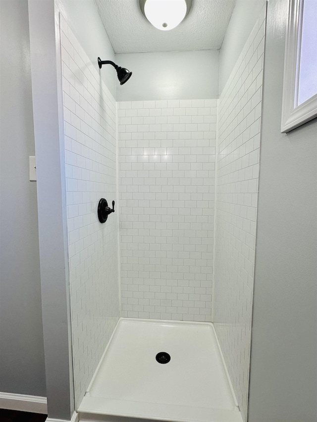 full bathroom featuring a textured ceiling and a tile shower