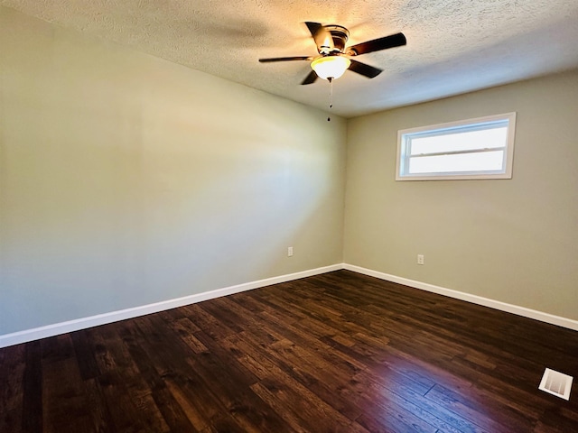 spare room featuring dark wood-type flooring, visible vents, baseboards, and a ceiling fan