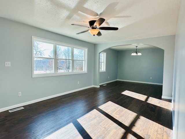 spare room featuring baseboards, visible vents, arched walkways, and dark wood-style flooring