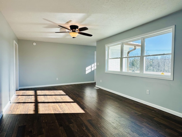 spare room featuring dark wood-type flooring, a textured ceiling, baseboards, and a ceiling fan