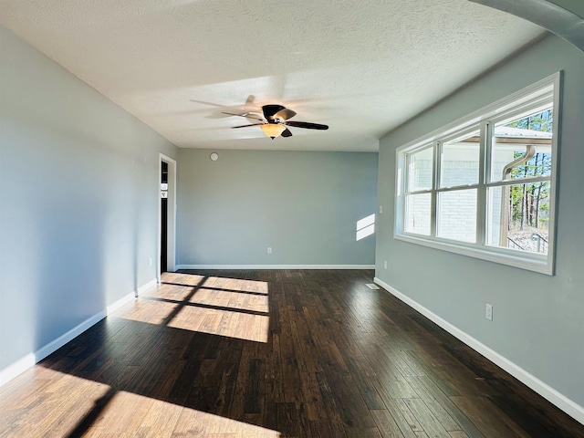 unfurnished room with a textured ceiling, ceiling fan, dark wood-type flooring, and baseboards