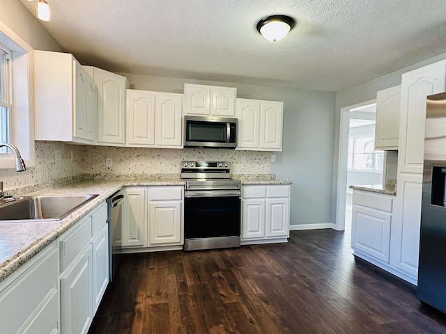 kitchen featuring dark wood-style flooring, white cabinetry, stainless steel appliances, and a sink