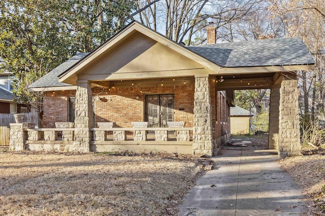 view of front facade featuring a shingled roof, brick siding, a chimney, and a fenced front yard