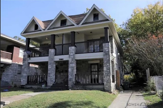 view of front of home with a porch, stone siding, and a front lawn