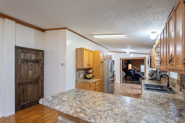 kitchen featuring crown molding, a peninsula, a sink, and stainless steel fridge with ice dispenser