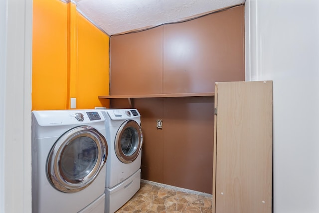 clothes washing area featuring a textured ceiling, laundry area, separate washer and dryer, and stone finish floor