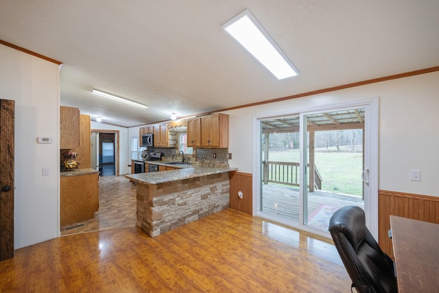 kitchen featuring a wainscoted wall, a peninsula, appliances with stainless steel finishes, and a sink