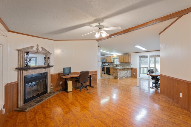 office featuring light wood-style flooring, ornamental molding, a glass covered fireplace, and wainscoting