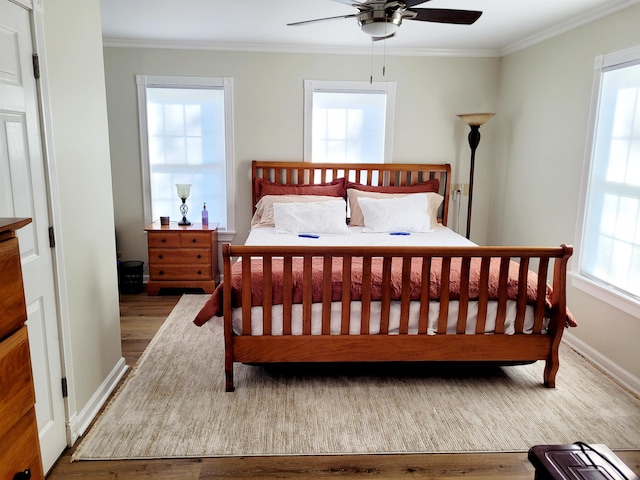 bedroom featuring baseboards, ornamental molding, and wood finished floors