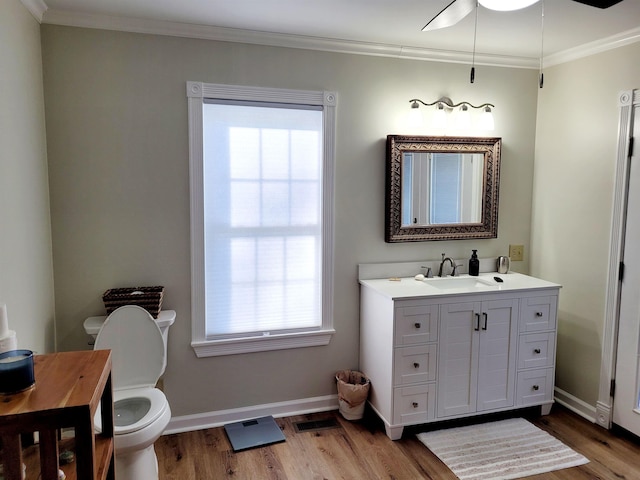 bathroom featuring toilet, wood finished floors, vanity, baseboards, and ornamental molding