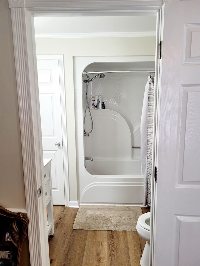 full bathroom with toilet, wood finished floors, vanity, shower / bath combo, and crown molding