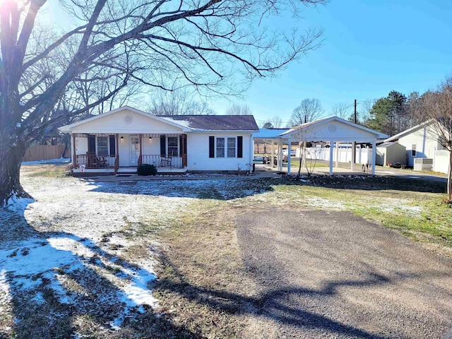 view of front facade with covered porch, dirt driveway, and a carport