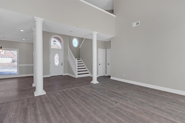 entrance foyer with visible vents, baseboards, stairs, dark wood-style floors, and ornate columns