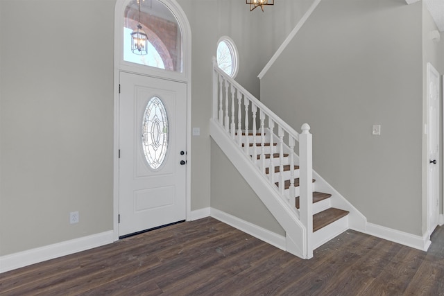 foyer entrance featuring a notable chandelier, baseboards, and dark wood-type flooring