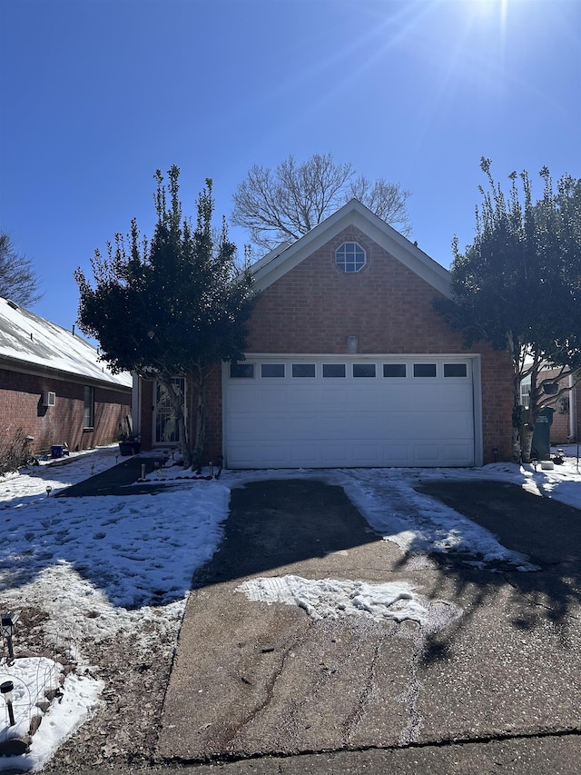 view of front of home featuring a garage, concrete driveway, and brick siding