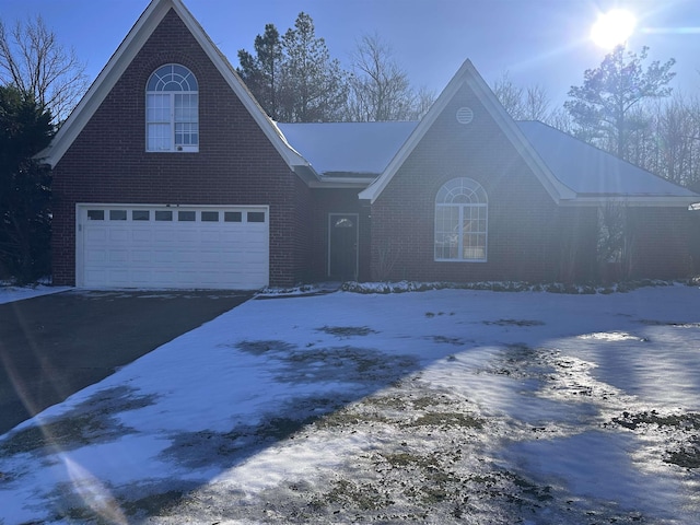 view of front of property featuring aphalt driveway, brick siding, and an attached garage