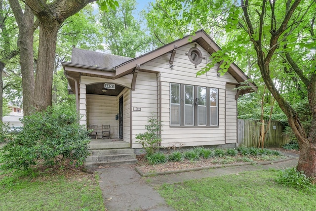 bungalow-style house featuring fence and roof with shingles