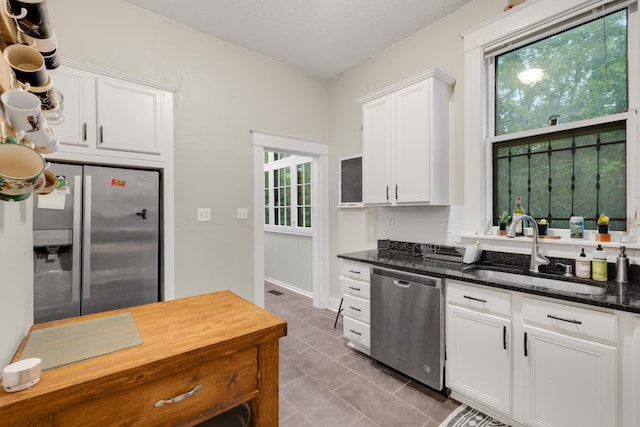 1151 Central Ave, Memphis, TN 38104 - kitchen featuring light tile patterned floors, dark stone countertops, stainless steel appliances, white cabinetry, and a sink