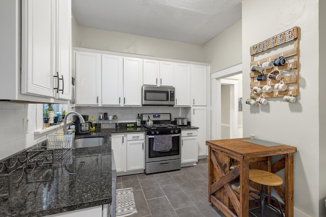 1151 Central Ave, Memphis, TN 38104 - kitchen featuring a sink, white cabinetry, appliances with stainless steel finishes, dark stone counters, and tasteful backsplash