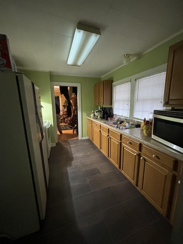 kitchen with stainless steel microwave, a sink, freestanding refrigerator, and brown cabinets