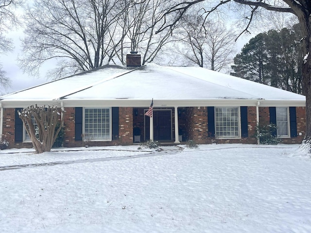 ranch-style home with cooling unit, brick siding, and a chimney