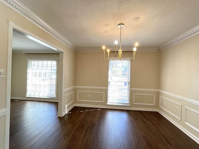 unfurnished dining area featuring dark wood-style floors, a textured ceiling, ornamental molding, and a notable chandelier