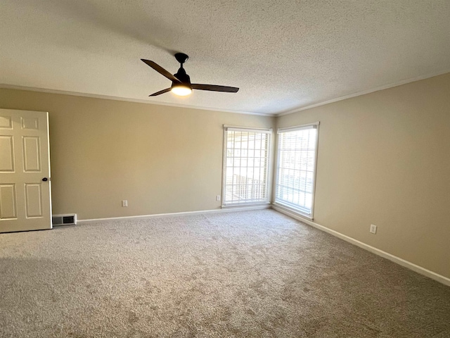 carpeted empty room featuring ceiling fan, a textured ceiling, visible vents, baseboards, and crown molding