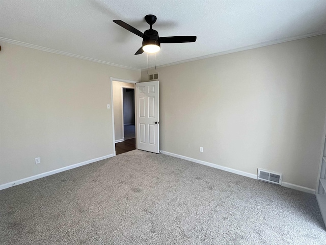 carpeted spare room featuring ornamental molding, a ceiling fan, visible vents, and baseboards