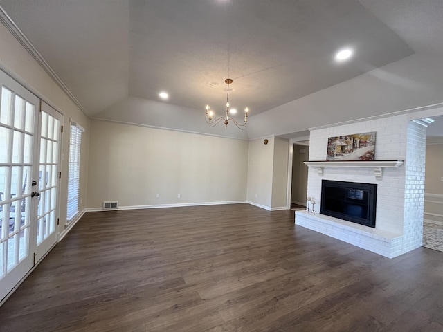 unfurnished living room with vaulted ceiling, a brick fireplace, dark wood finished floors, and visible vents