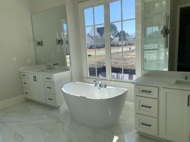 bathroom with marble finish floor, two vanities, a sink, and a soaking tub