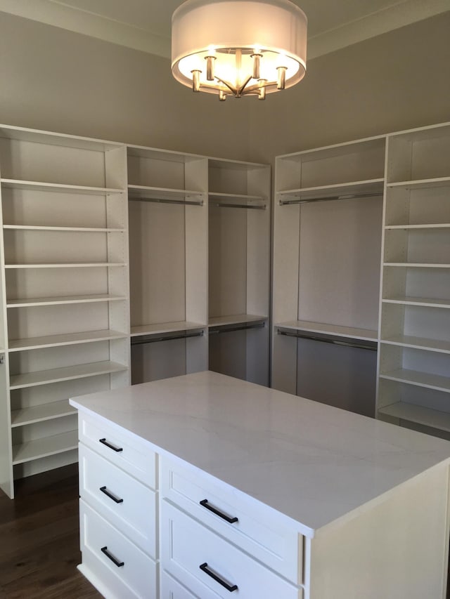 spacious closet featuring dark wood-type flooring and a notable chandelier