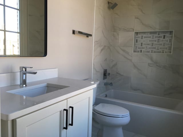 bathroom with washtub / shower combination, vanity, and toilet