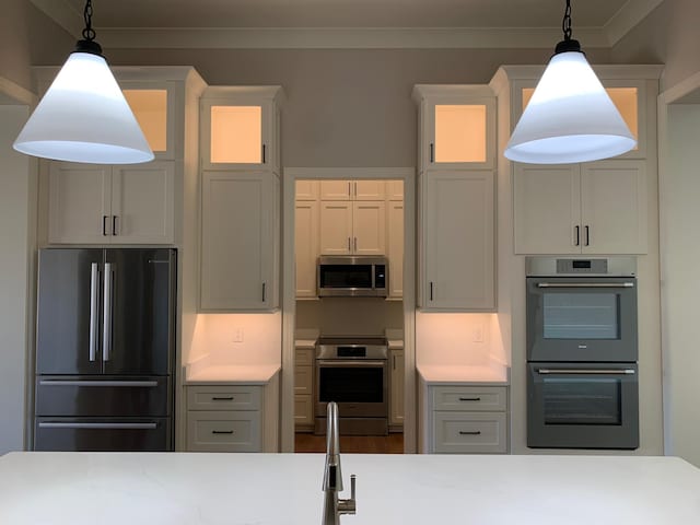 kitchen featuring crown molding, pendant lighting, stainless steel appliances, and light countertops