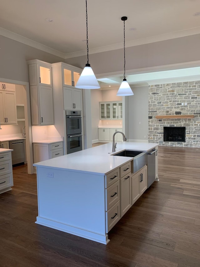 kitchen featuring white cabinetry, a center island with sink, glass insert cabinets, and light countertops