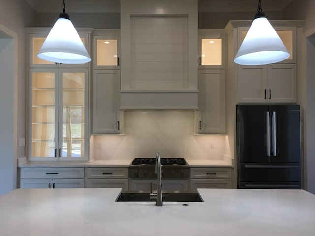 kitchen with hanging light fixtures, light countertops, a sink, and freestanding refrigerator