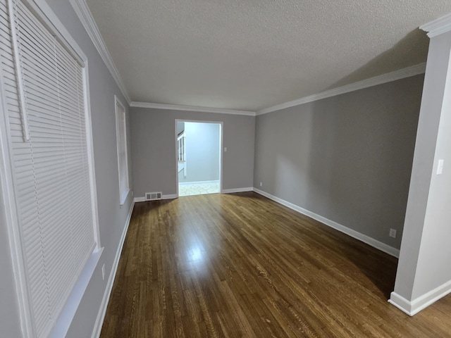 unfurnished room with ornamental molding, dark wood finished floors, a textured ceiling, and baseboards