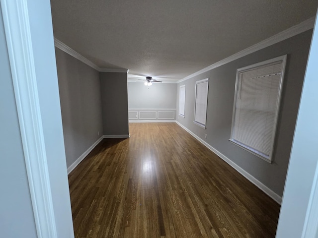 spare room featuring baseboards, ceiling fan, ornamental molding, dark wood-type flooring, and a textured ceiling