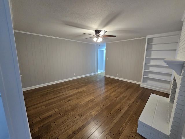 unfurnished living room with ceiling fan, ornamental molding, dark wood-style flooring, a textured ceiling, and a brick fireplace