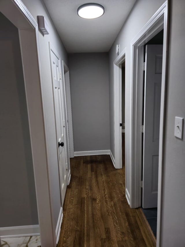 hall with baseboards and dark wood-type flooring