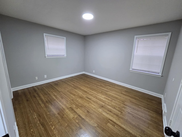 spare room featuring dark wood-style floors and baseboards