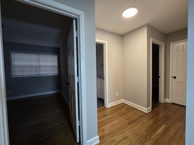 hall featuring baseboards and dark wood-style flooring