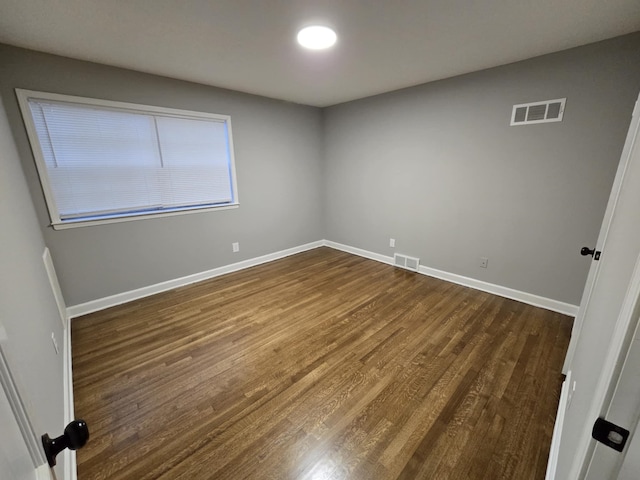 spare room with baseboards, visible vents, and dark wood-type flooring