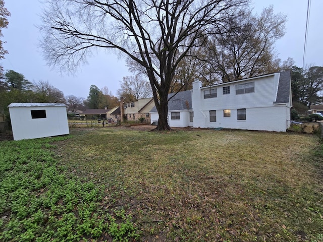 view of yard featuring a storage unit, fence, and an outbuilding