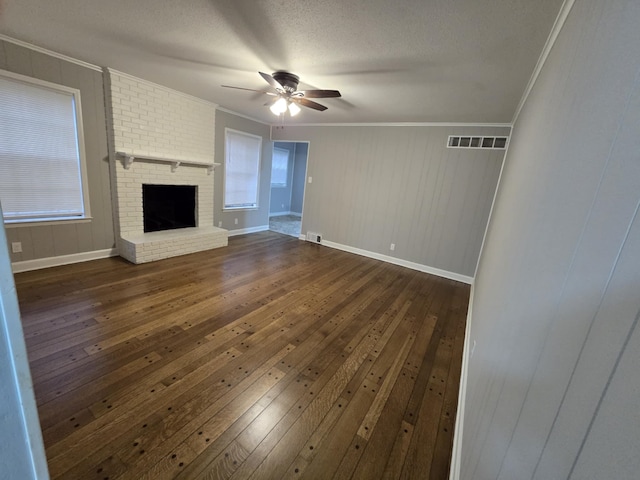 unfurnished living room featuring a fireplace, visible vents, dark wood finished floors, and crown molding